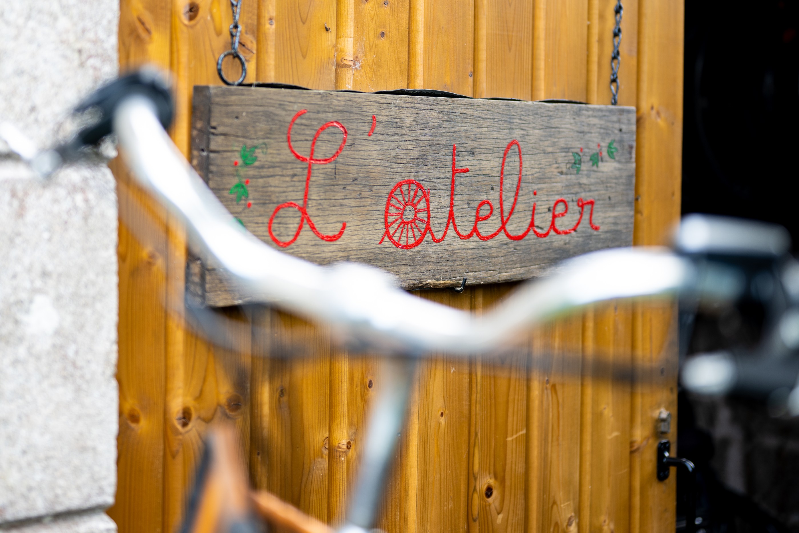 Panneau L'atelier accroché sur un mur en bois